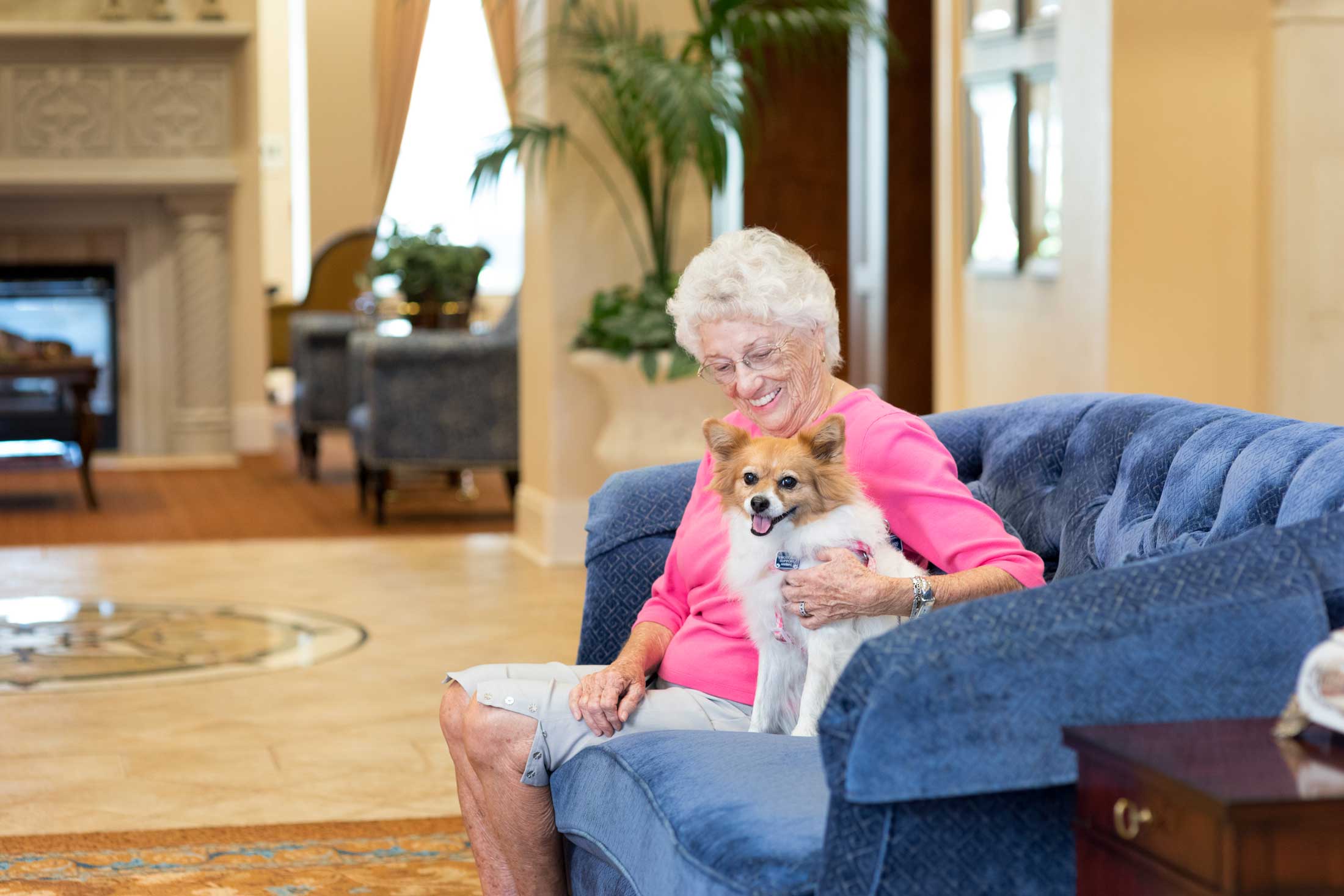 senior woman sitting on a couch with her dog