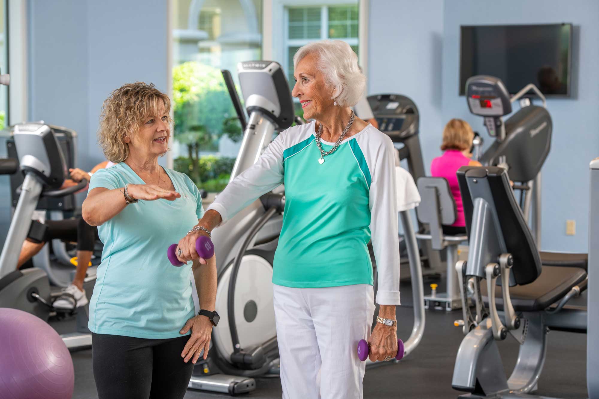 a fitness instructor guiding a senior woman in her exercises